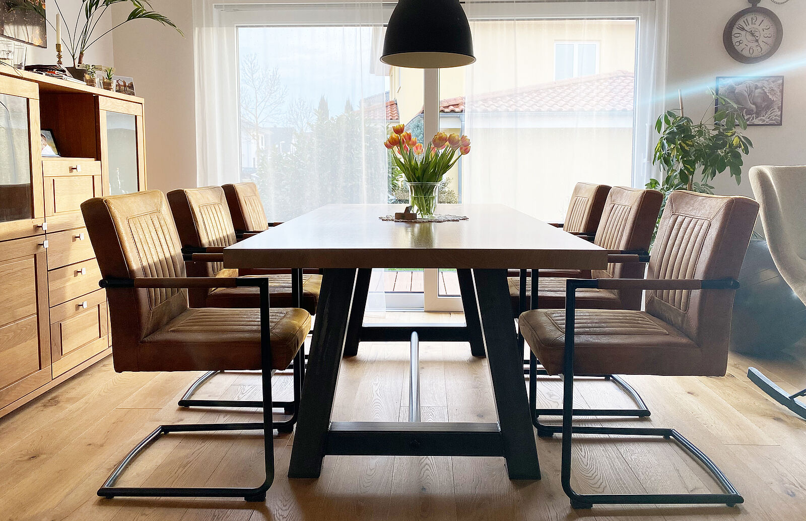 Esszimmer mit Holztisch, 6 Lederstühlen und Blumenvase